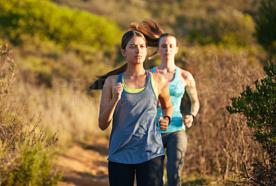Buy stock photo Shot of two young woman out for a cross country run