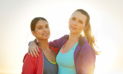 Buy stock photo Portrait of two smiling young friends standing arm in arm while out for a run