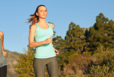 Buy stock photo Shot of two young woman out for a cross country run