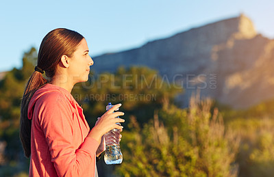 Buy stock photo Shot of a young woman taking a water break while out for a cross country run