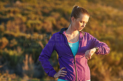 Buy stock photo Shot of a young woman checking her time while out for a trail run