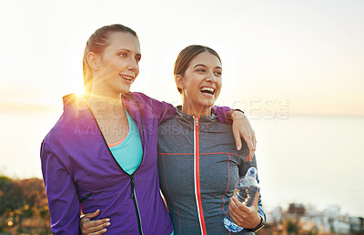 Buy stock photo Shot of two smiling young friends standing arm in arm while out for a run