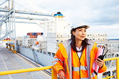 Buy stock photo Shot of a woman in workwear standing on a commercial dock holding a walkie talkie