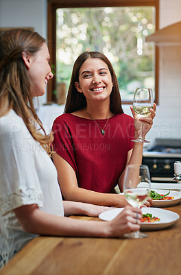 Buy stock photo Shot of two friends sitting at the kitchen table eating pizza and drinking wine