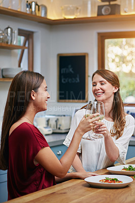 Buy stock photo Shot of two friends sitting at the kitchen table eating pizza and drinking wine