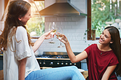 Buy stock photo Shot of two friends in a kitchen toasting each other while drinking wine
