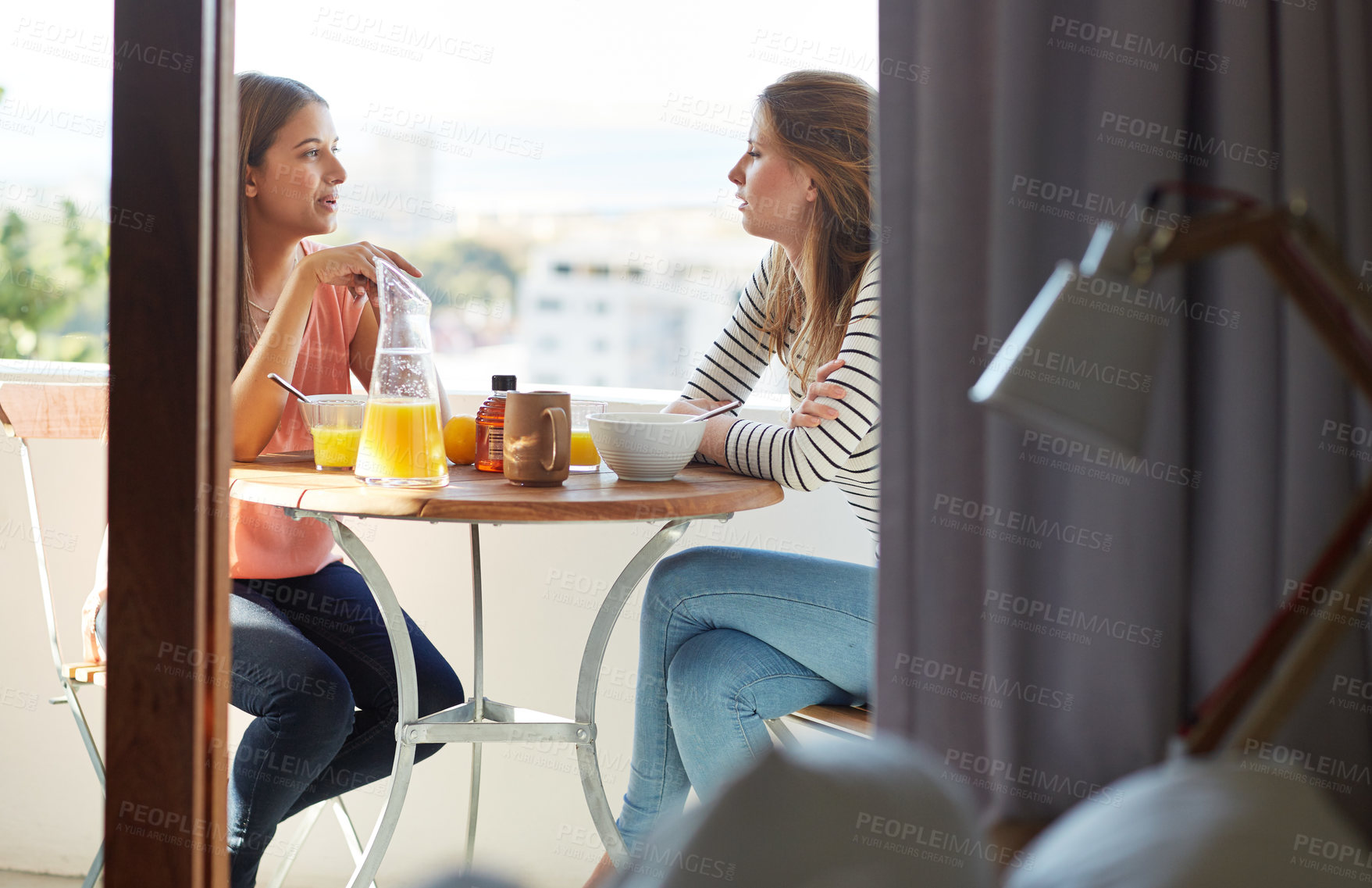 Buy stock photo Shot of two friends eating breakfast together on a balcony