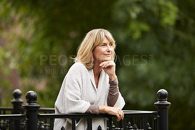 Buy stock photo Shot of a mature woman leaning against the railing of her front porch