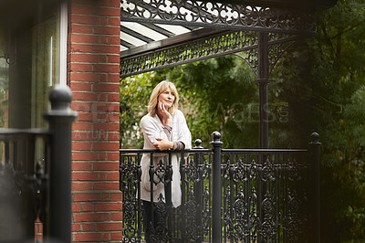 Buy stock photo Shot of a mature woman leaning against the railing of her front porch