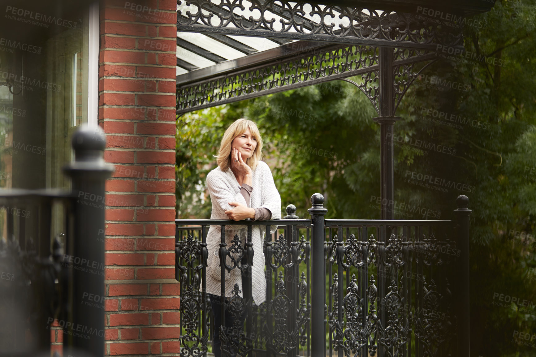 Buy stock photo Shot of a mature woman leaning against the railing of her front porch