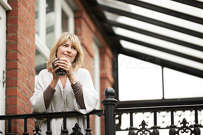 Buy stock photo Shot of a mature woman leaning against the railing of her front porch drinking a coffee