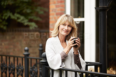 Buy stock photo Portrait of a mature woman leaning against the railing of her front porch drinking a coffee