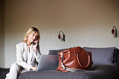 Buy stock photo Shot of a mature businesswoman sitting on a hotel bed talking on her cellphone