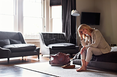 Buy stock photo Shot of an exhausted businesswoman sitting on a bed in a hotel