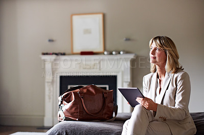 Buy stock photo Shot of a mature businesswoman sitting on a hotel bed using a digital tablet