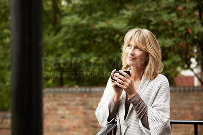 Buy stock photo Shot of a mature woman sitting on her balcony drinking coffee