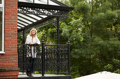 Buy stock photo Shot of a mature woman leaning on her balcony enjoying the morning