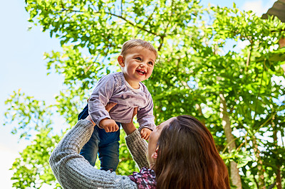 Buy stock photo Shot of a mother holding her smiling baby girl up in the air outdoors