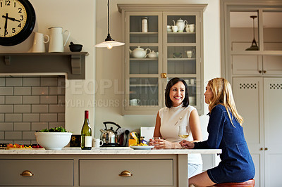 Buy stock photo Shot of a two friends talking and drinking wine in a kitchen