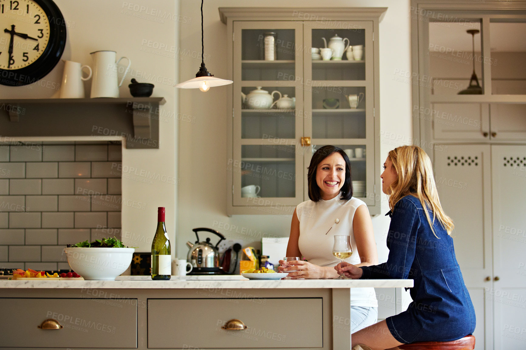 Buy stock photo Shot of a two friends talking and drinking wine in a kitchen