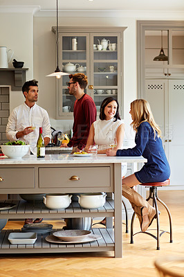 Buy stock photo Shot of a group of friends talking and drinking wine together while preparing dinner