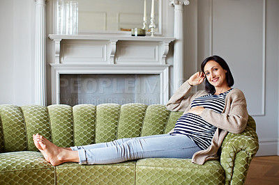 Buy stock photo Portrait of a smiling pregnant woman sitting on her sofa
