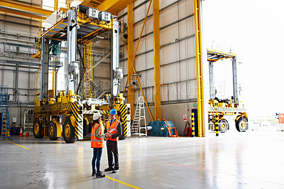 Buy stock photo Shot of two warehouse workers talking together over a digital tablet