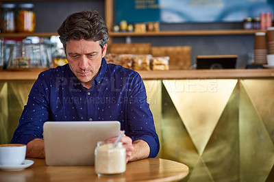 Buy stock photo Shot of a man working on a digital tablet in a cafe