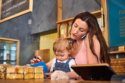 Buy stock photo Shot of a woman talking on the phone in a bakery with her little girl next to her on the counter