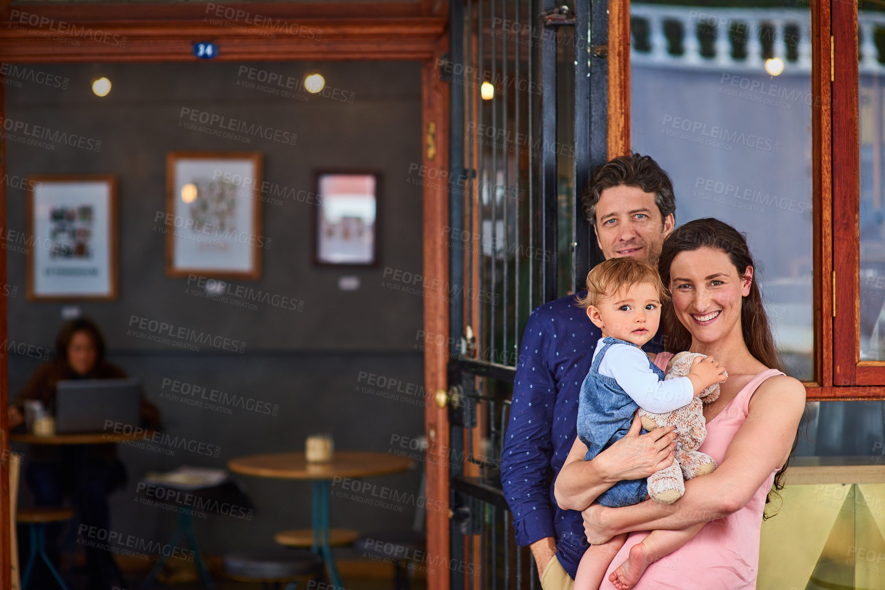 Buy stock photo Portrait of smiling couple and their little girl standing in front of their bakery