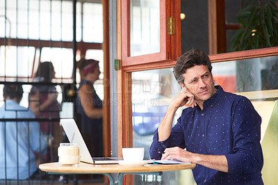 Buy stock photo Shot of a man working on a laptop in a cafe
