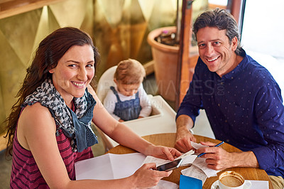 Buy stock photo Portrait of a couple and their baby daughter sitting at a table in a cafe
