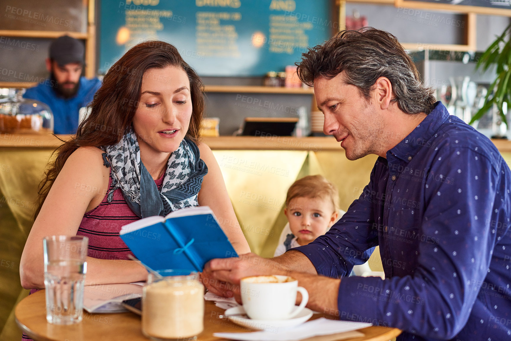 Buy stock photo Shot of a couple and their baby daughter sitting at a table in a cafe