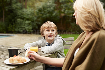 Buy stock photo Shot of a grandmother and her grandson have lunch at a table in her yard
