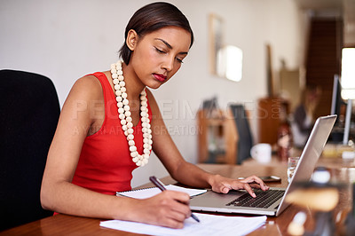 Buy stock photo Shot of a young woman working on a laptop in an office