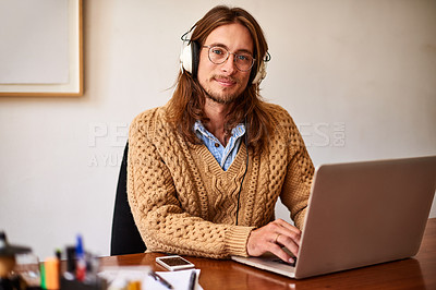 Buy stock photo Portrait of a young designer working on a laptop and listening to music on headphones in an office