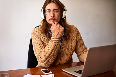 Buy stock photo Portrait of a young designer working on a laptop and listening to music on headphones in an office