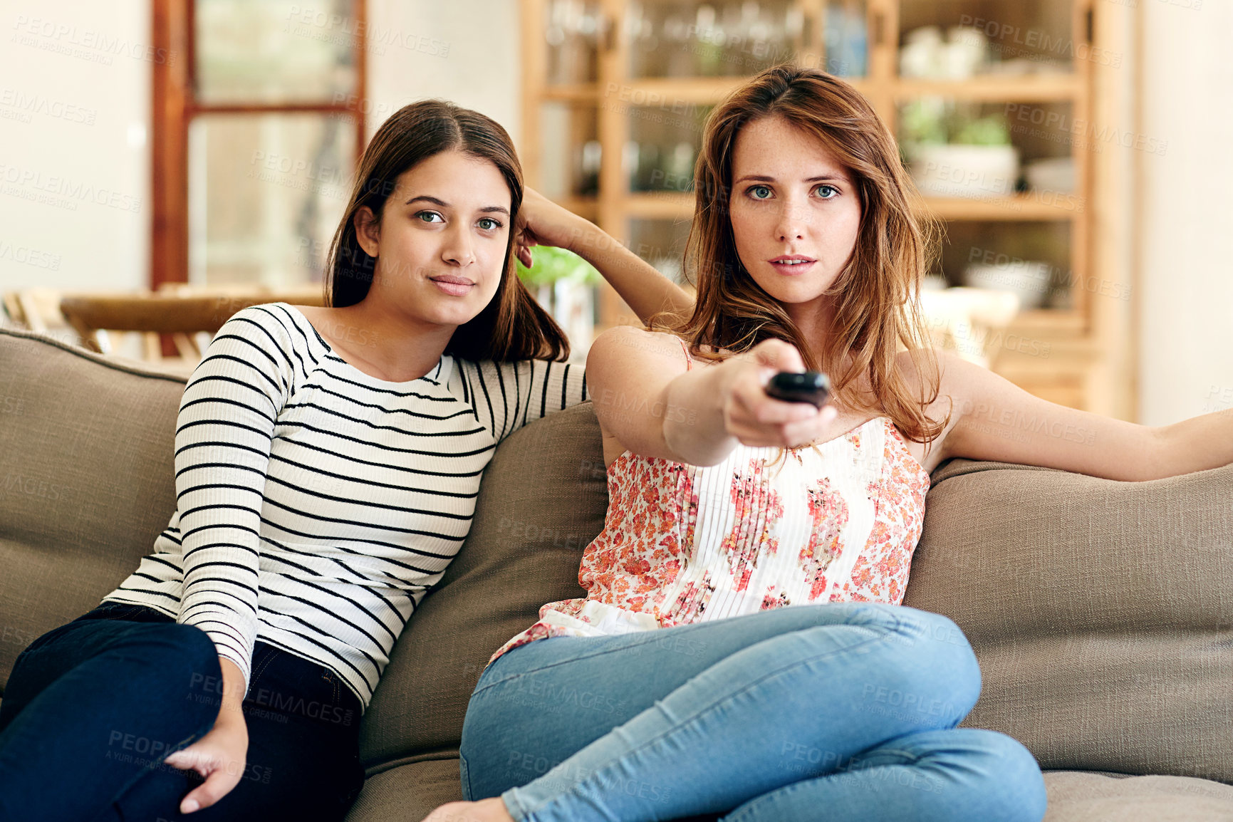 Buy stock photo Shot of two friends sitting on the sofa watching tv