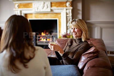Buy stock photo Shot of a woman drinking wine while talking with her daughter on the living room sofa