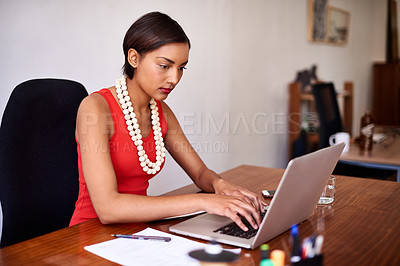 Buy stock photo Shot of a young woman working on a laptop in an office