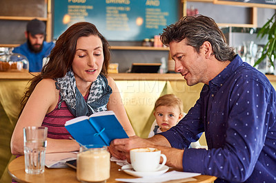 Buy stock photo Shot of a couple and their baby daughter sitting at a table in a cafe