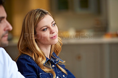 Buy stock photo Shot of a young couple listening to conversation at home