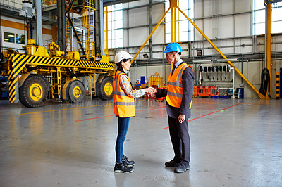 Buy stock photo Shot of two warehouse workers shanking hands together inside of a large warehouse