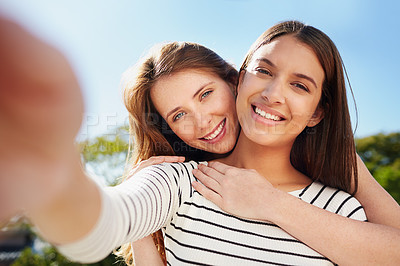 Buy stock photo Shot of two friends taking a selfie together while standing outside