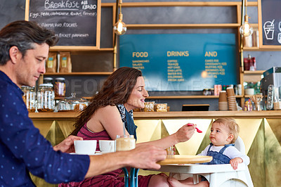Buy stock photo Shot of a couple and their baby daughter sitting at a table in a cafe