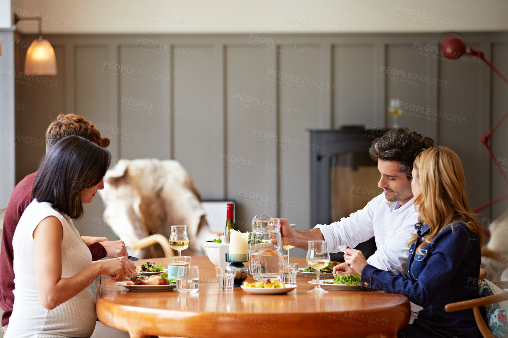 Buy stock photo Shot of a group of friends enjoying a home-cooked dinner together