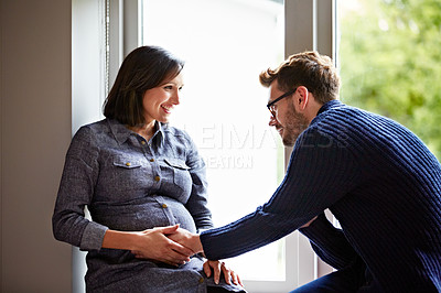 Buy stock photo Shot of a husband rubbing his pregnant wife's tummy at home