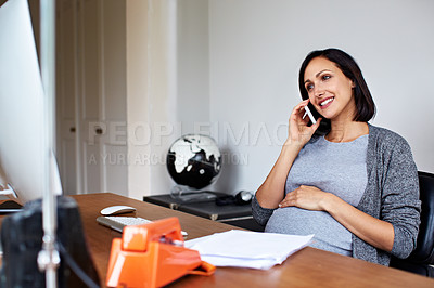 Buy stock photo Shot of a pregnant women using her phone while working in her home office