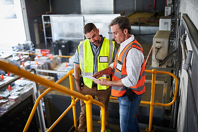 Buy stock photo Shot of two warehouse workers standing on stairs discussing papework