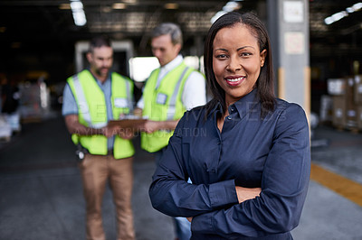 Buy stock photo Portrait of a warehouse manager standing arms folded with workers in the background